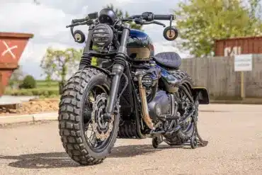 Thornton Hundred Adventure Bobber mit grobstolligen Reifen, breiten Speichenrädern und individueller Ausstattung auf einem asphaltierten Platz.