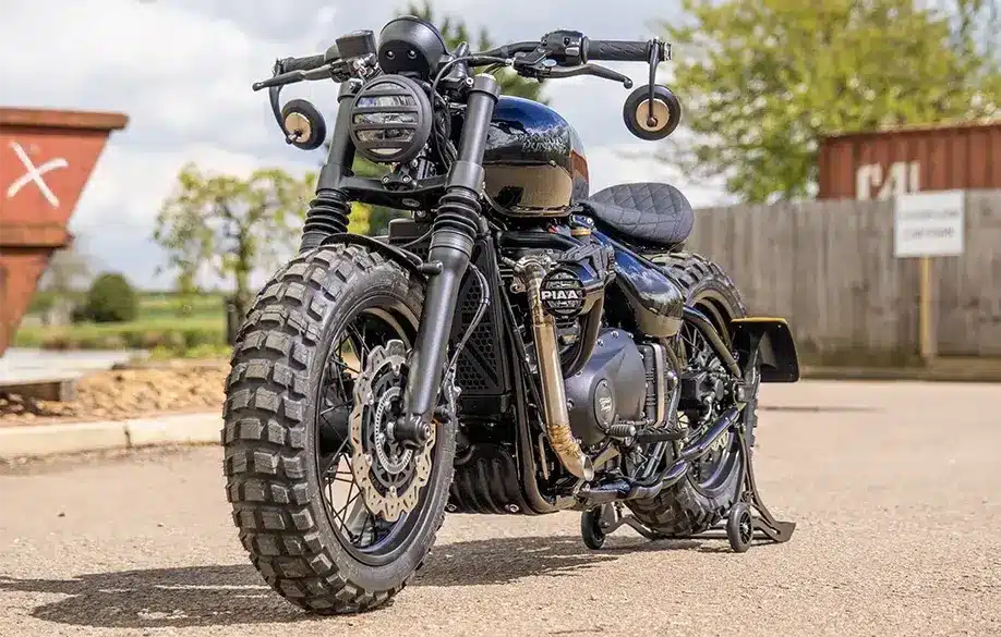 Thornton Hundred Adventure Bobber mit grobstolligen Reifen, breiten Speichenrädern und individueller Ausstattung auf einem asphaltierten Platz.