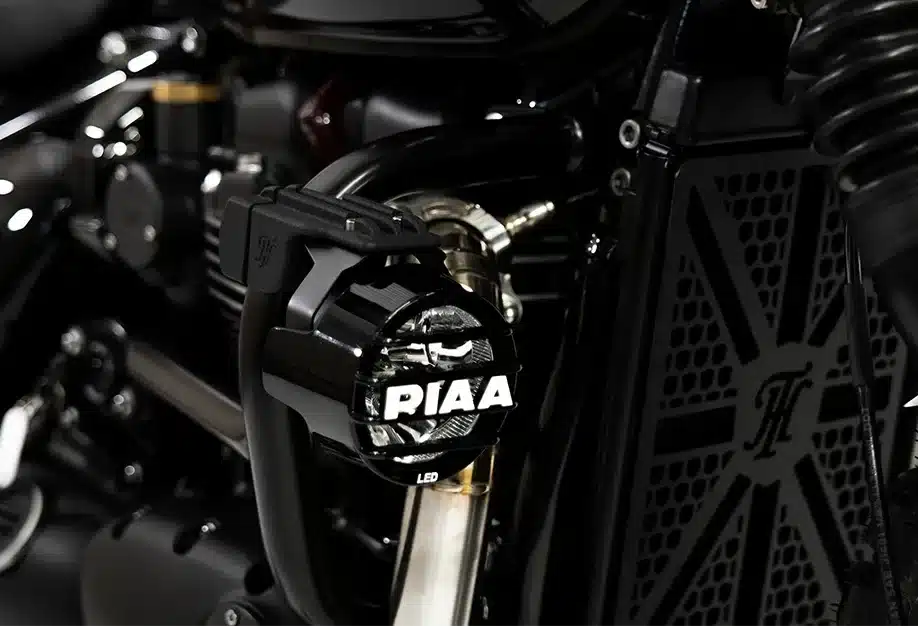 Nahaufnahme einer PIAA-Zusatzleuchte an einer Thornton Hundred Adventure Bobber, vor dem Kühler mit Logo.