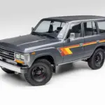 Restaurierter Toyota Land Cruiser FJ62 aus 1988 in Grau mit klassischen Streifen, Seitenansicht vor neutralem Hintergrund