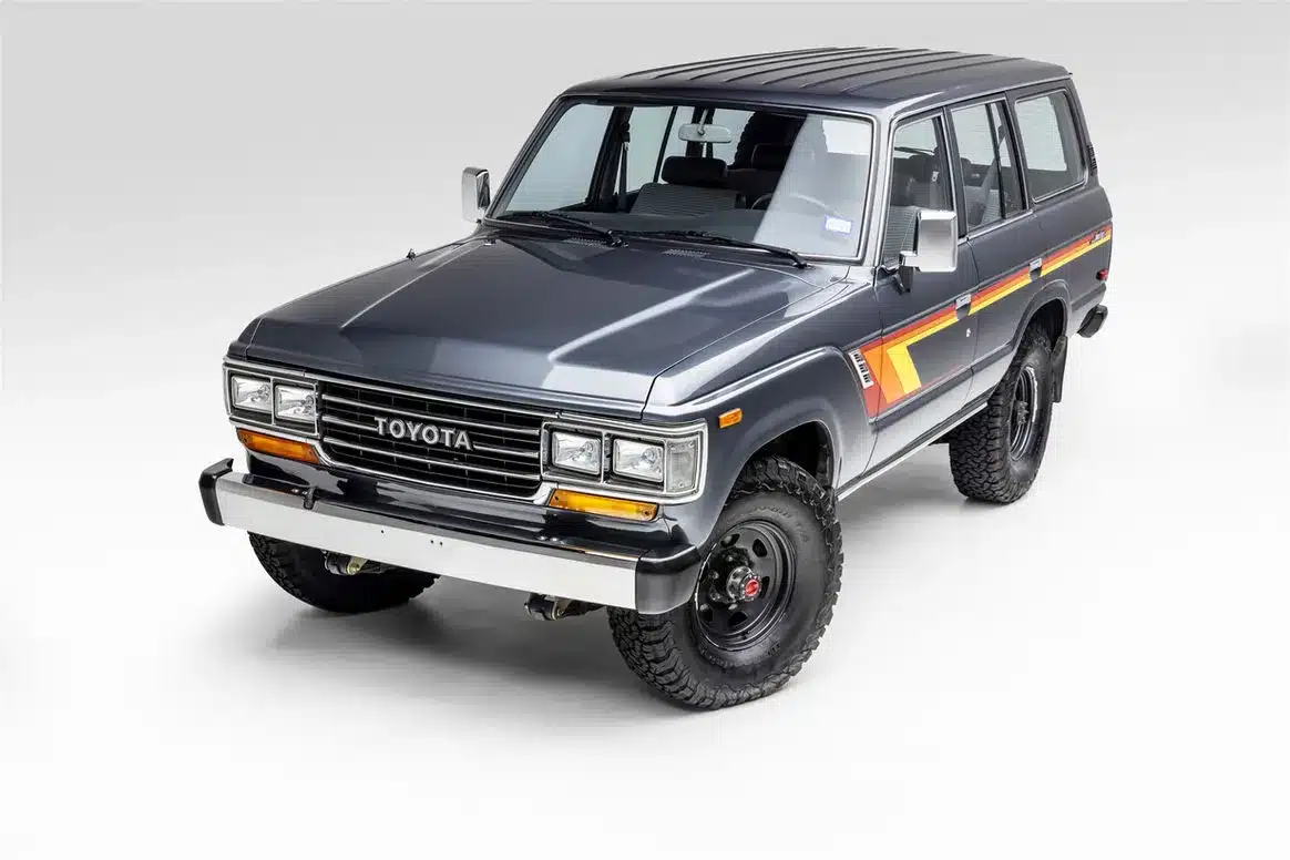 Vollrestaurierter Toyota Land Cruiser FJ62 aus dem Jahr 1988 in dunkelgrau mit farbigen Seitenstreifen, fotografiert im Studio