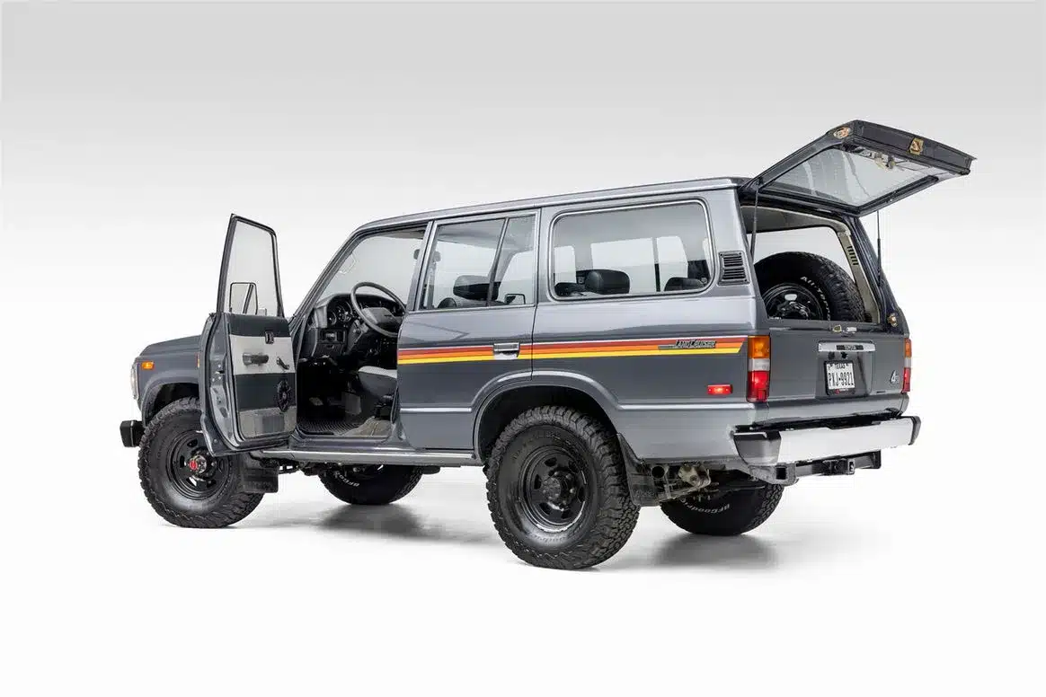Restaurierter Toyota Land Cruiser FJ62 von 1988, seitliche Ansicht mit geöffneter Fahrertür und Heckklappe, zeigt Innenraum und robuste Karosserie.
