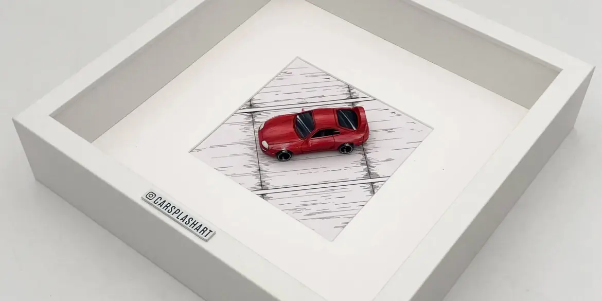Gerahmtes Modell eines roten Toyota Supra Mk IV im Maßstab 1:64 in einem weißen Kastenrahmen von oben fotografiert