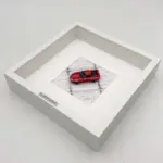 Gerahmtes Modell eines roten Toyota Supra Mk IV im Maßstab 1:64 in einem weißen Kastenrahmen von oben fotografiert