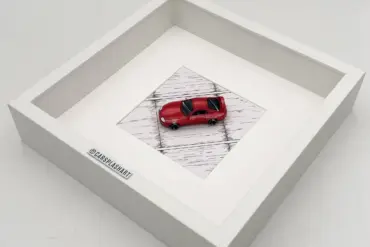 Gerahmtes Modell eines roten Toyota Supra Mk IV im Maßstab 1:64 in einem weißen Kastenrahmen von oben fotografiert