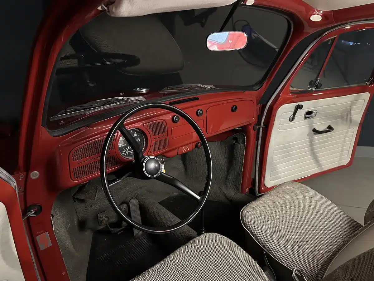 Gut erhaltener Innenraum eines 1969er Volkswagen Spaarkever mit schwarzem Lenkrad und grauen Sitzen.