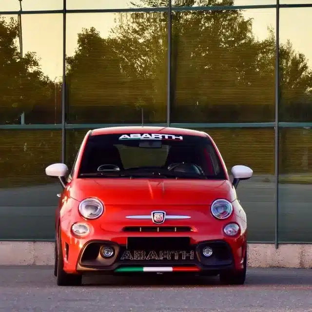 Roter Abarth 500 aus der Frontansicht, sportlich und dynamisch, vor Glasfassade geparkt