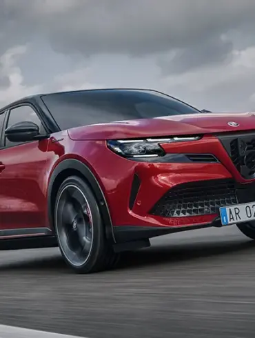 Alfa Romeo Junior Elettrica, rotes kompaktes Elektroauto, fährt dynamisch auf einer Straße