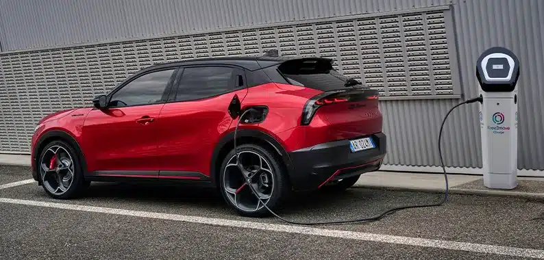 Roter Alfa Romeo Junior Elettrica beim Ladevorgang an einer öffentlichen Ladesäule.