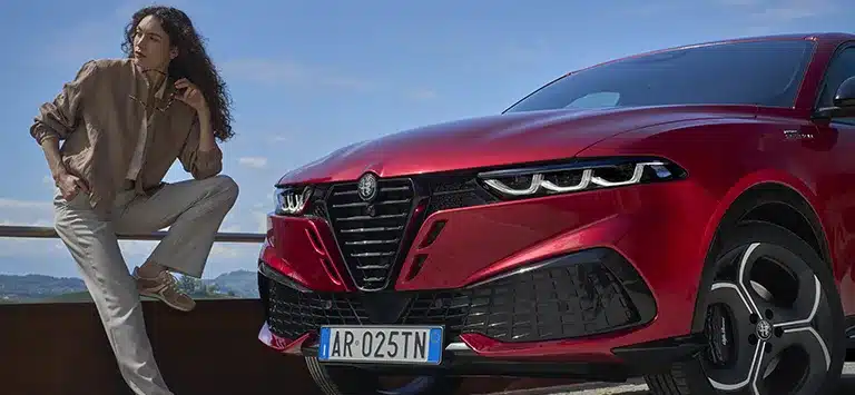 Der neue Alfa Romeo Tonale in Rot mit Scudetto-Kühlergrill und LED-Matrix-Scheinwerfern vor bergiger Landschaft