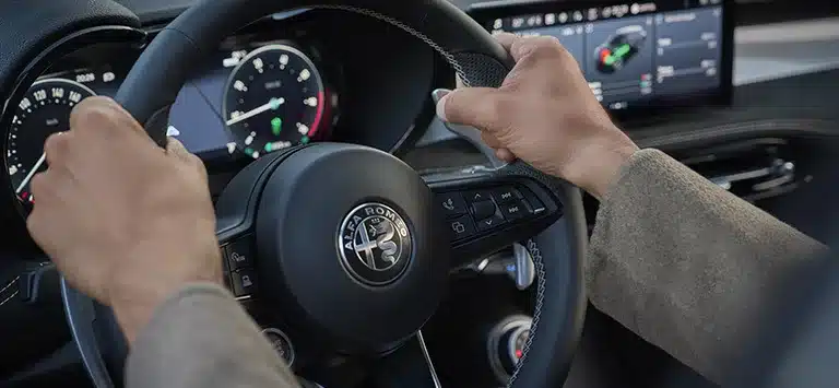 Fahrer hält das Lenkrad des Alfa Romeo Tonale, digitale Anzeigen im Hintergrund
