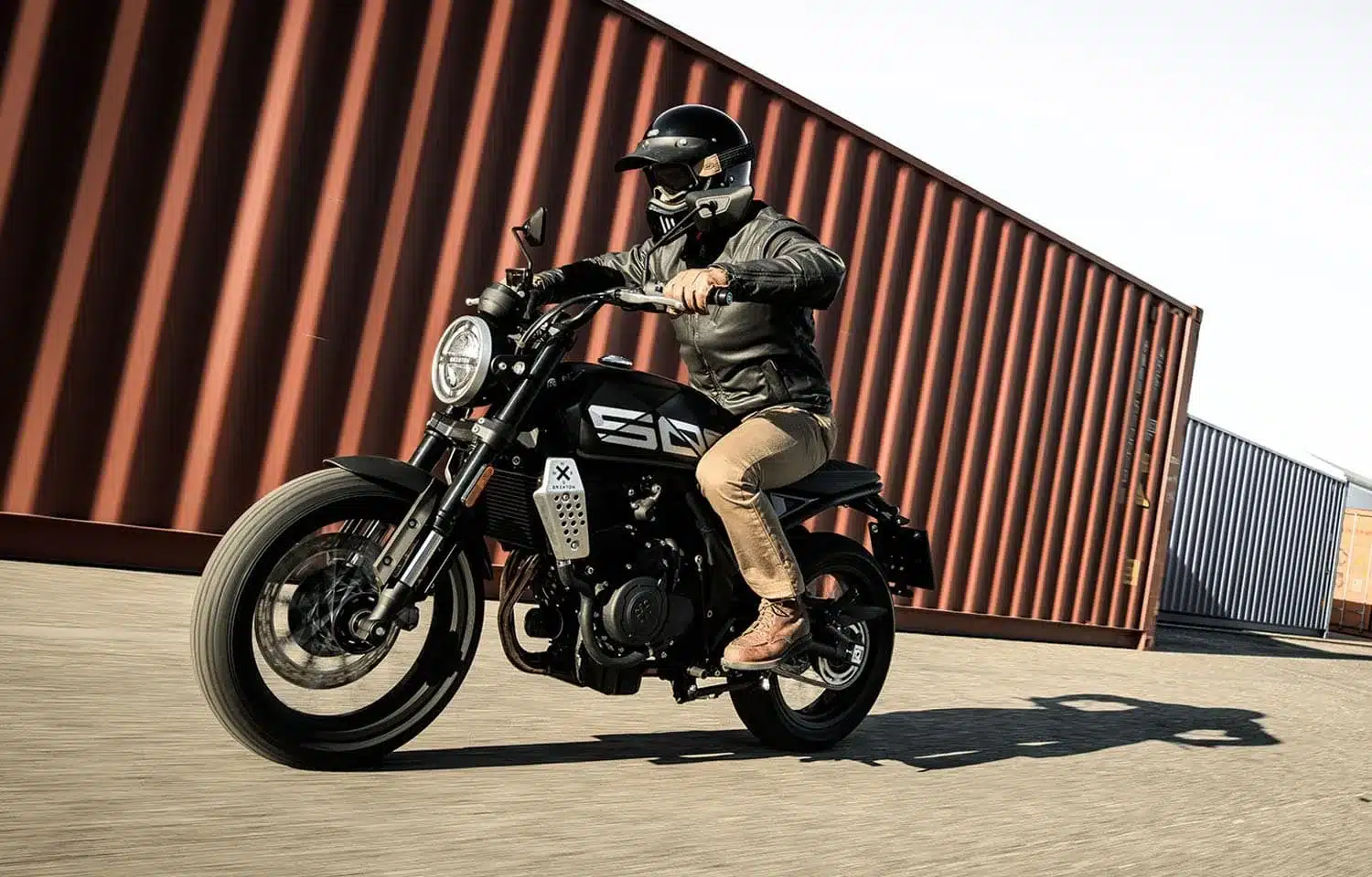 Fahrer auf einer Brixton Crossfire 500 X Motorrad, seitliche Ansicht während der Fahrt, moderne Optik, schwarze Farbe.