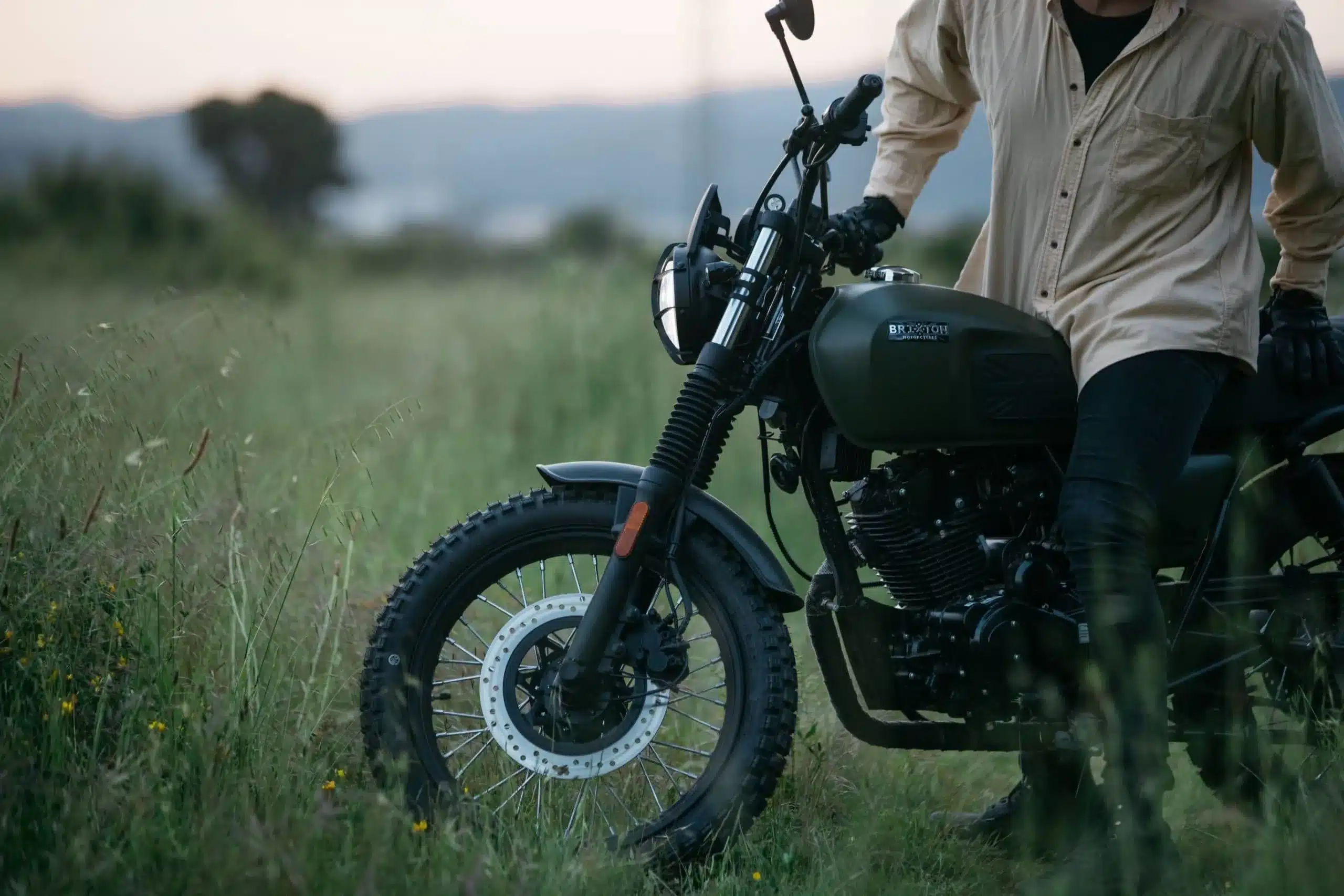 Brixton Felsberg 125 Scrambler-Motorrad im Gras, seitliche Ansicht mit Fahrer