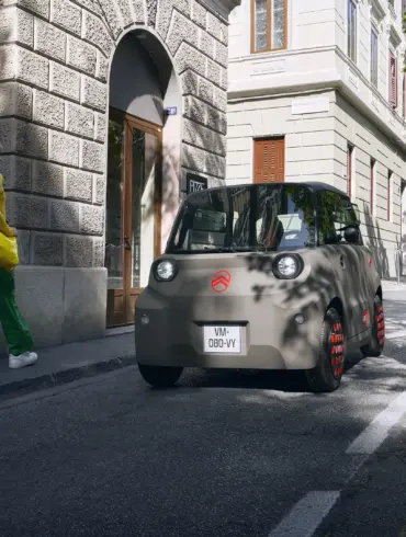 Citroën Ami, ein kompaktes Elektrofahrzeug, fährt auf einer städtischen Straße.
