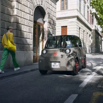Citroën Ami, ein kompaktes Elektrofahrzeug, fährt auf einer städtischen Straße.