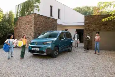 Citroën ë-Berlingo wird an einer Wallbox vor einem modernen Haus geladen, Familie im Vordergrund.