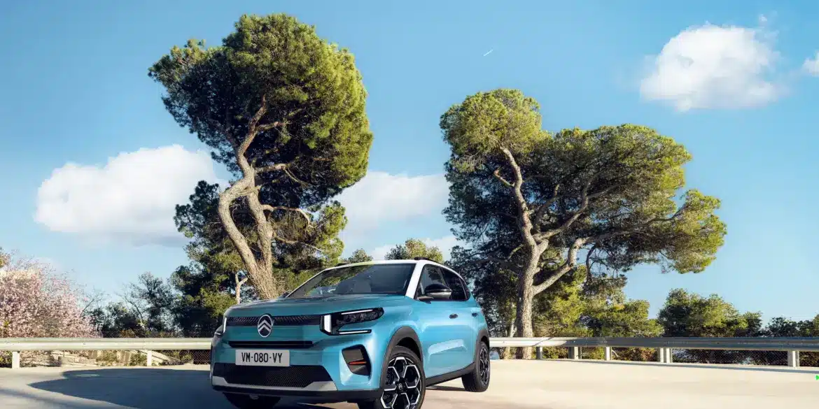 Citroën ë-C3 in blauer Lackierung auf einem Parkplatz, Bäume im Hintergrund, strahlender Himmel.