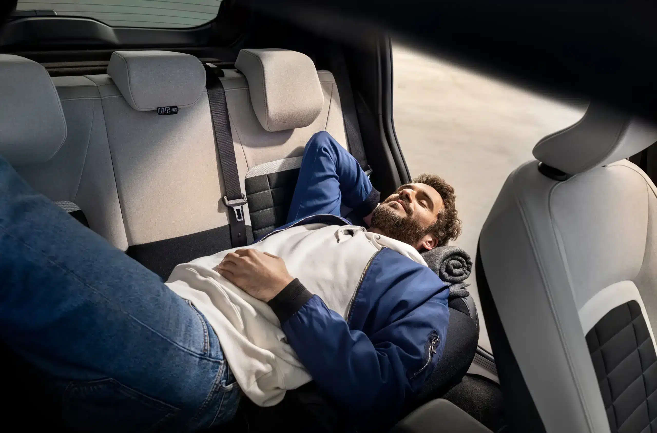 Mann entspannt auf der Rückbank eines Citroën ë-C3 und zeigt den großzügigen Innenraum.