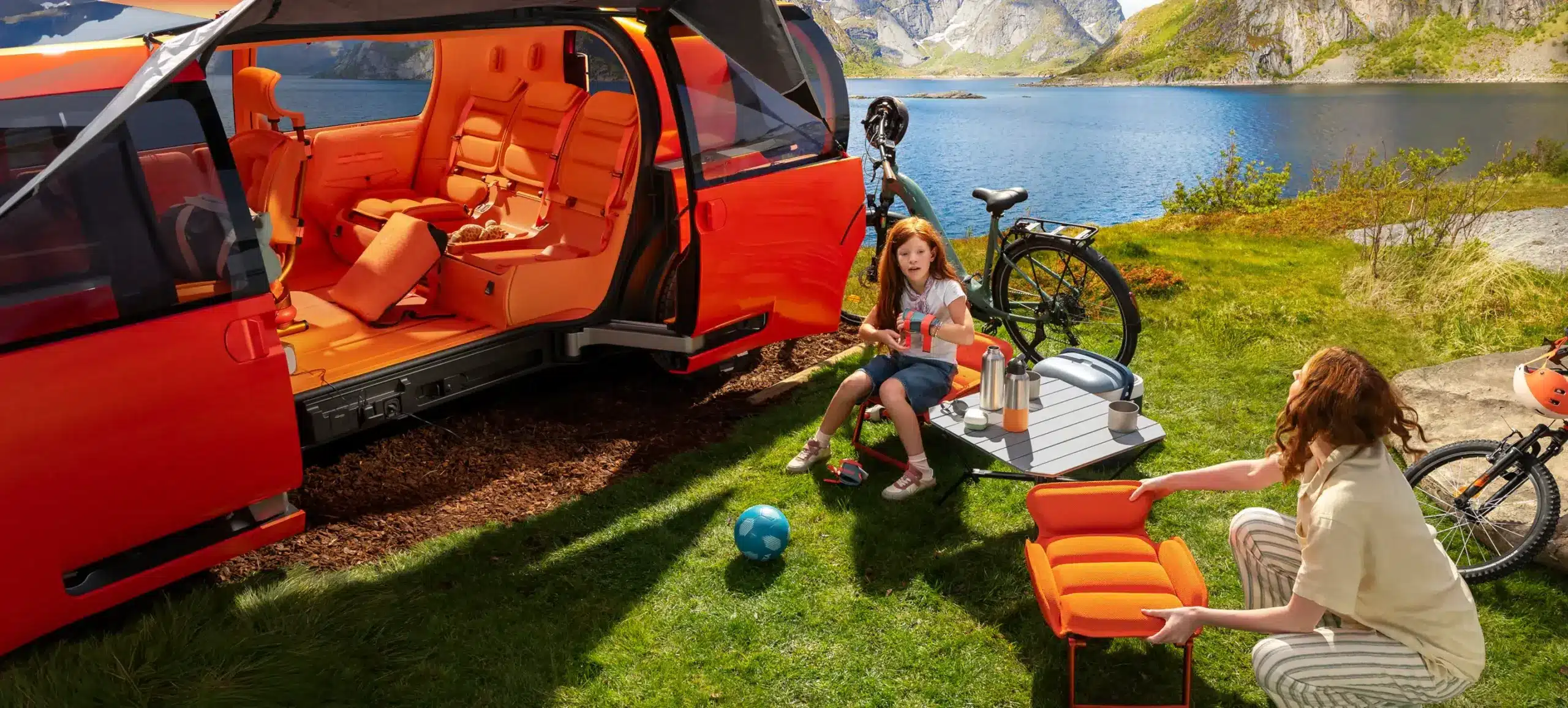 Offener Citroën ELO Concept mit ausgeklappten Sitzen und Outdoor-Ausstattung am Seeufer, Kind und Frau entspannen sich beim Camping.