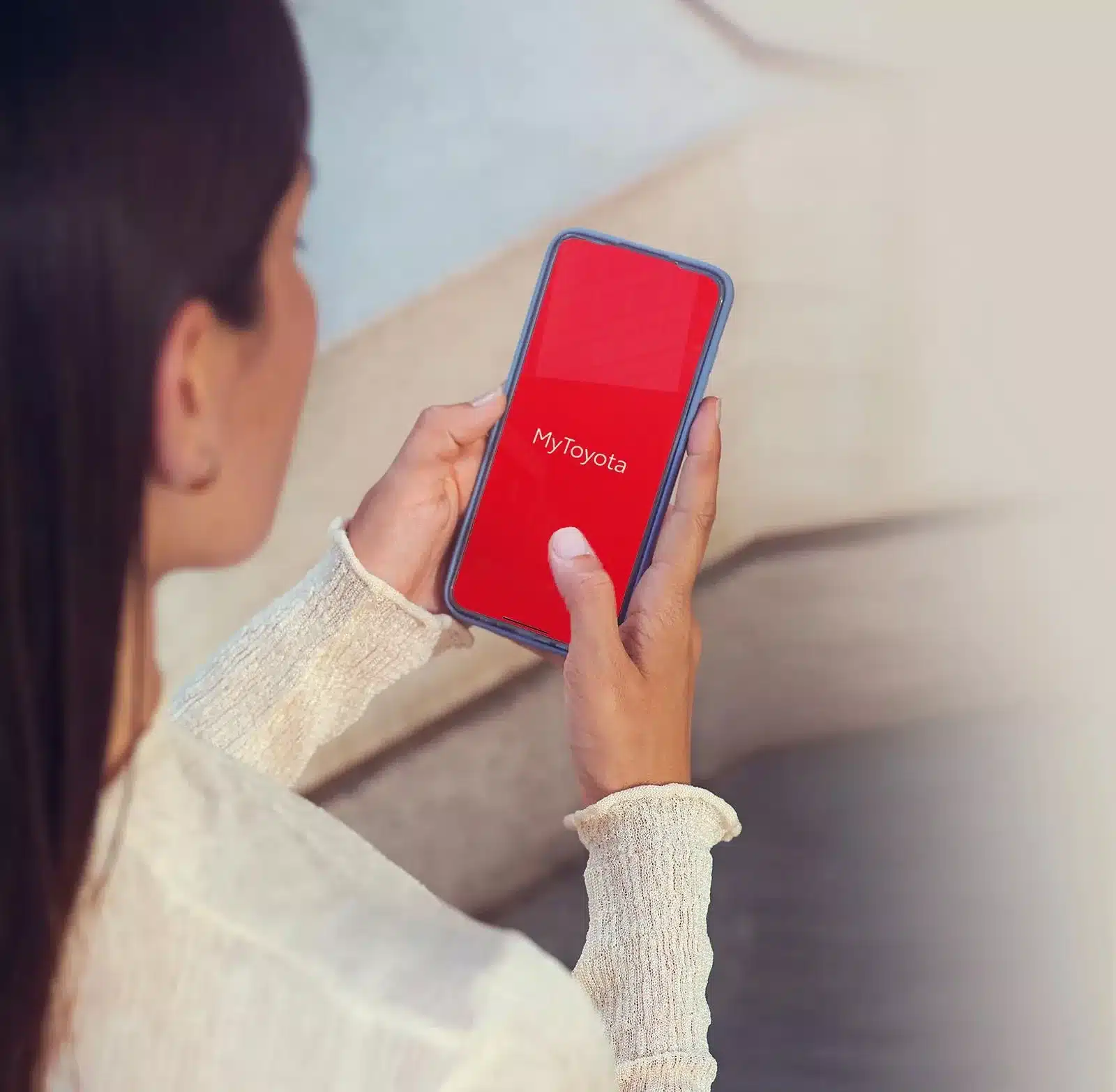 Frau hält Smartphone mit geöffneter MyToyota-App in der Hand