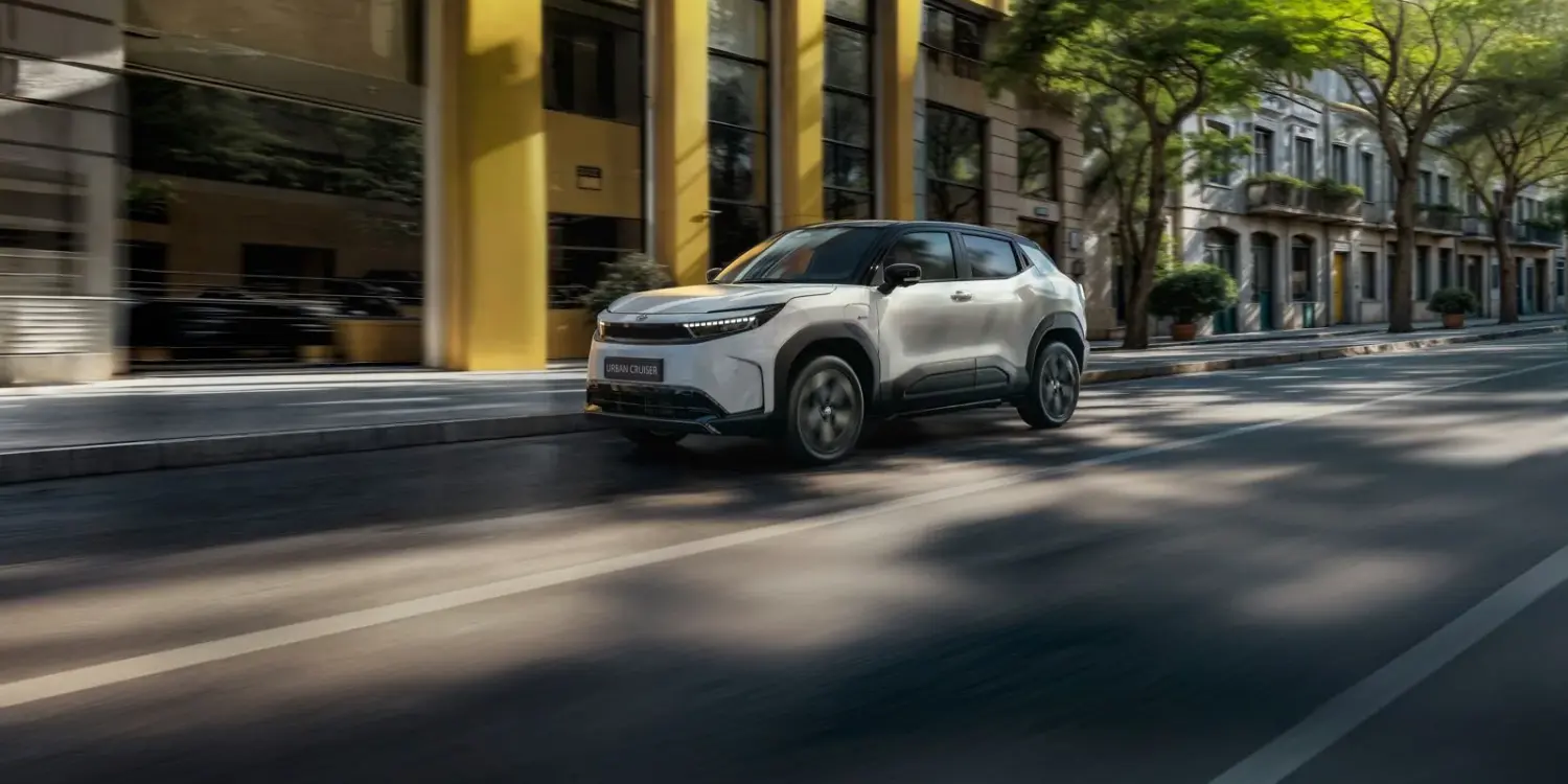 Toyota Urban Cruiser Elektro-SUV fährt auf einer städtischen Straße vor modernen Gebäuden