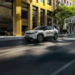 Toyota Urban Cruiser Elektro-SUV fährt auf einer städtischen Straße vor modernen Gebäuden