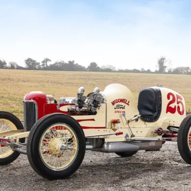 Seitenansicht des 1932 McDowell Ford Special „A“ Sprint Car, historischer Rennwagen mit offener Bauweise und Startnummer 25, aufgenommen auf einem Feldweg vor ländlicher Kulisse