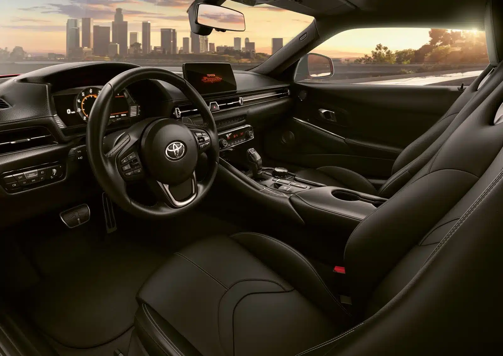Das Cockpit und Interieur des Toyota GR Supra 2025, aufgenommen bei Sonnenuntergang, mit Fokus auf das sportliche Lenkrad, die Instrumententafel und die Vordersitze.