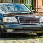 Dunkelgrüner Mercedes-Benz 600 SEL W140 Baujahr 1991, Frontansicht vor Backsteinfassade