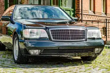 Dunkelgrüner Mercedes-Benz 600 SEL W140 Baujahr 1991, Frontansicht vor Backsteinfassade