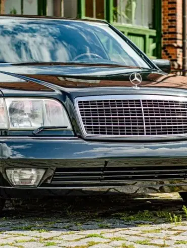 Dunkelgrüner Mercedes-Benz 600 SEL W140 Baujahr 1991, Frontansicht vor Backsteinfassade