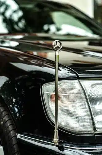 Nahaufnahme des vorderen linken Kotflügels und Scheinwerfers eines Mercedes-Benz W140 600 SEL mit Mercedes-Stern auf der Motorhaube.