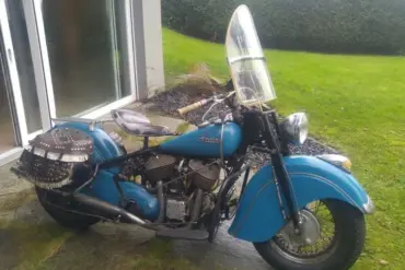 Blaue Indian Chief 1948 mit Windschutzscheibe und Ledersatteltaschen vor Terrasse