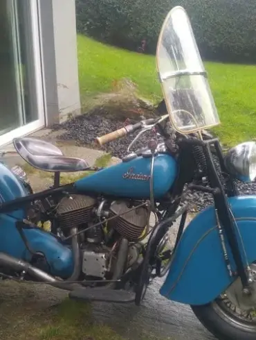 Blaue Indian Chief 1948 mit Windschutzscheibe und Ledersatteltaschen vor Terrasse