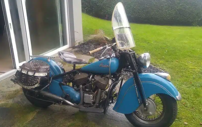 Blaue Indian Chief 1948 mit Windschutzscheibe und Ledersatteltaschen vor Terrasse