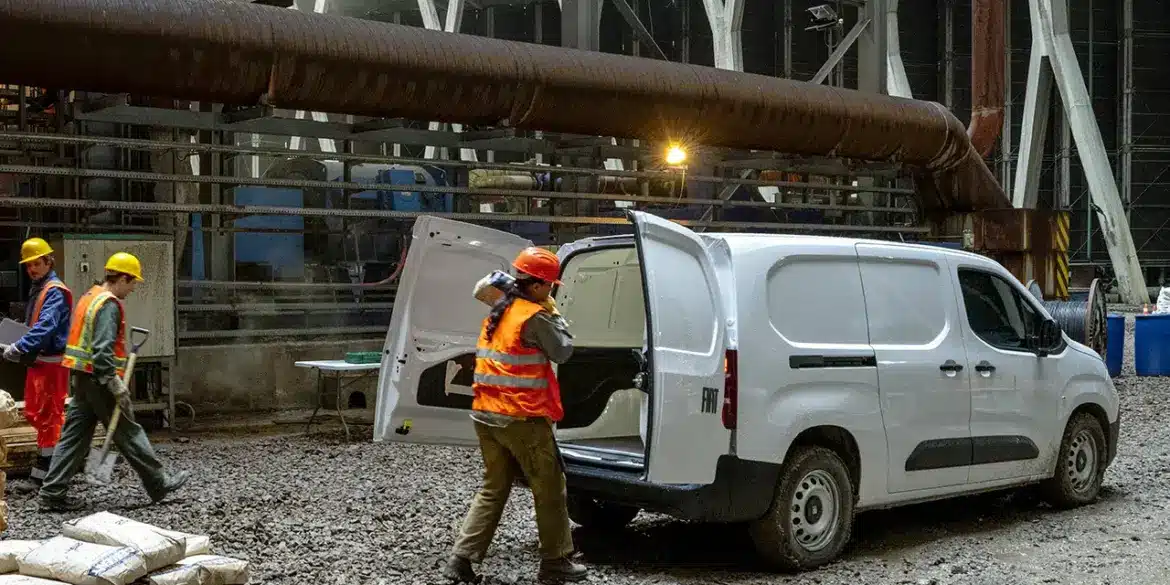Fiat Doblò 25th Anniversary als Kastenwagen auf einer Baustelle mit offenem Laderaum und Arbeiter mit Baumaterial.