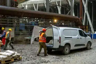 Fiat Doblò 25th Anniversary als Kastenwagen auf einer Baustelle mit offenem Laderaum und Arbeiter mit Baumaterial.