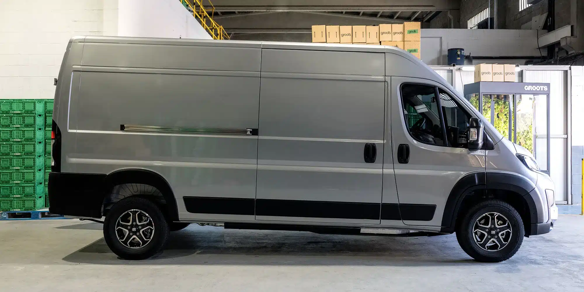 Fiat Ducato Transporter Seitenansicht in Lagerhalle, silberfarbenes Modell mit viel Stauraum.