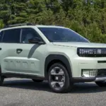 Fiat Grande Panda Benzin in heller Lackierung auf einer Straße, umgeben von Bäumen.