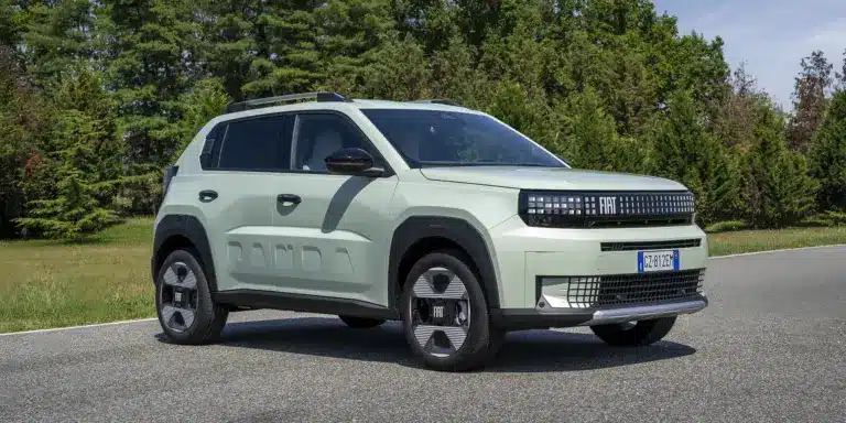 Fiat Grande Panda Benzin in heller Lackierung auf einer Straße, umgeben von Bäumen.