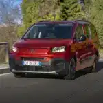 Roter Fiat Qubo L fährt auf einer Straße mit Bergen im Hintergrund.