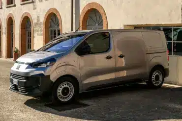 Fiat Scudo Transporter, Modelljahr 2024, geparkt vor einem historischen Gebäude mit Rundbogenfenstern.