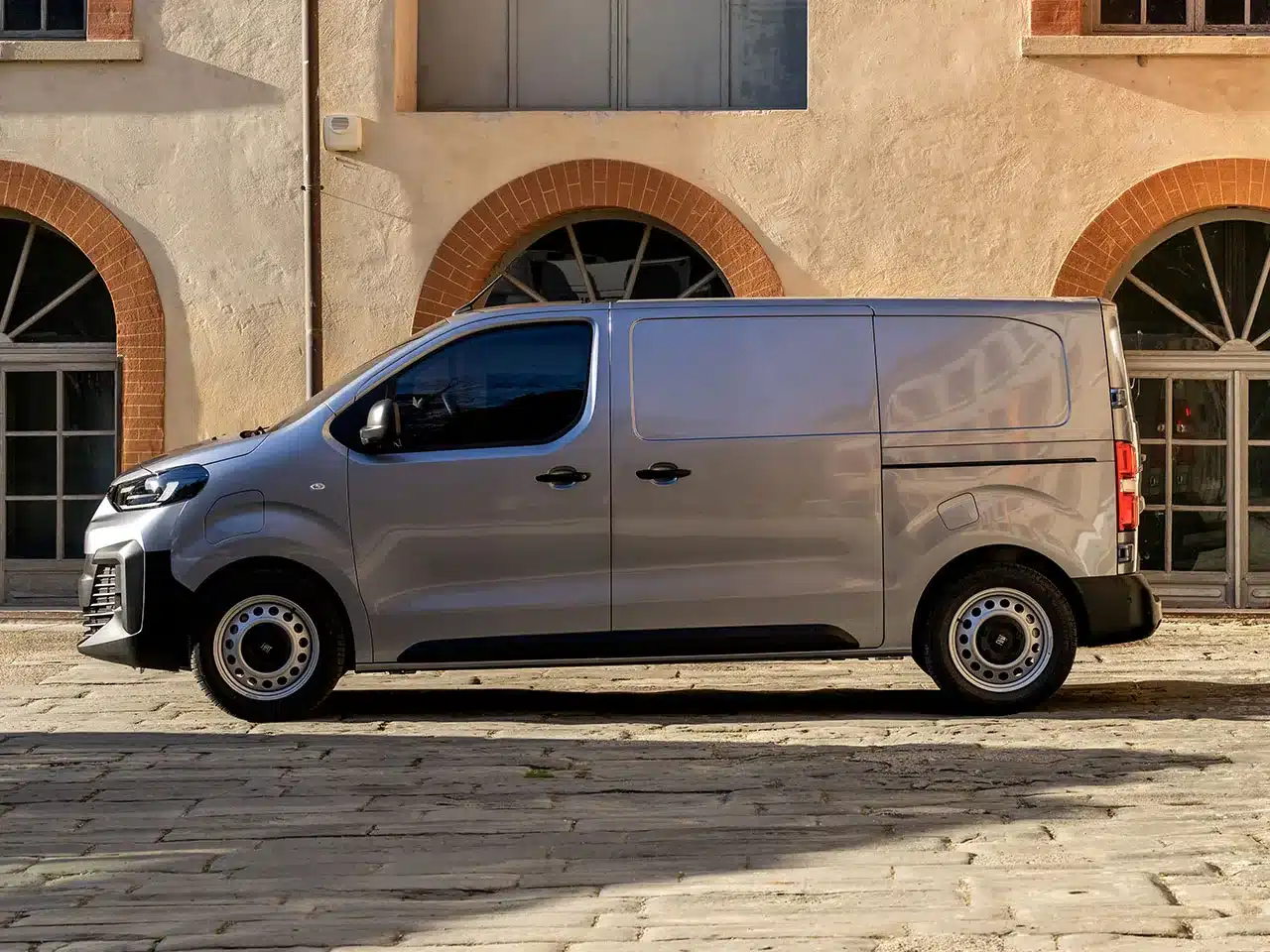 Fiat Scudo Transporter, silberfarben, Seitenansicht vor einem Altbau.