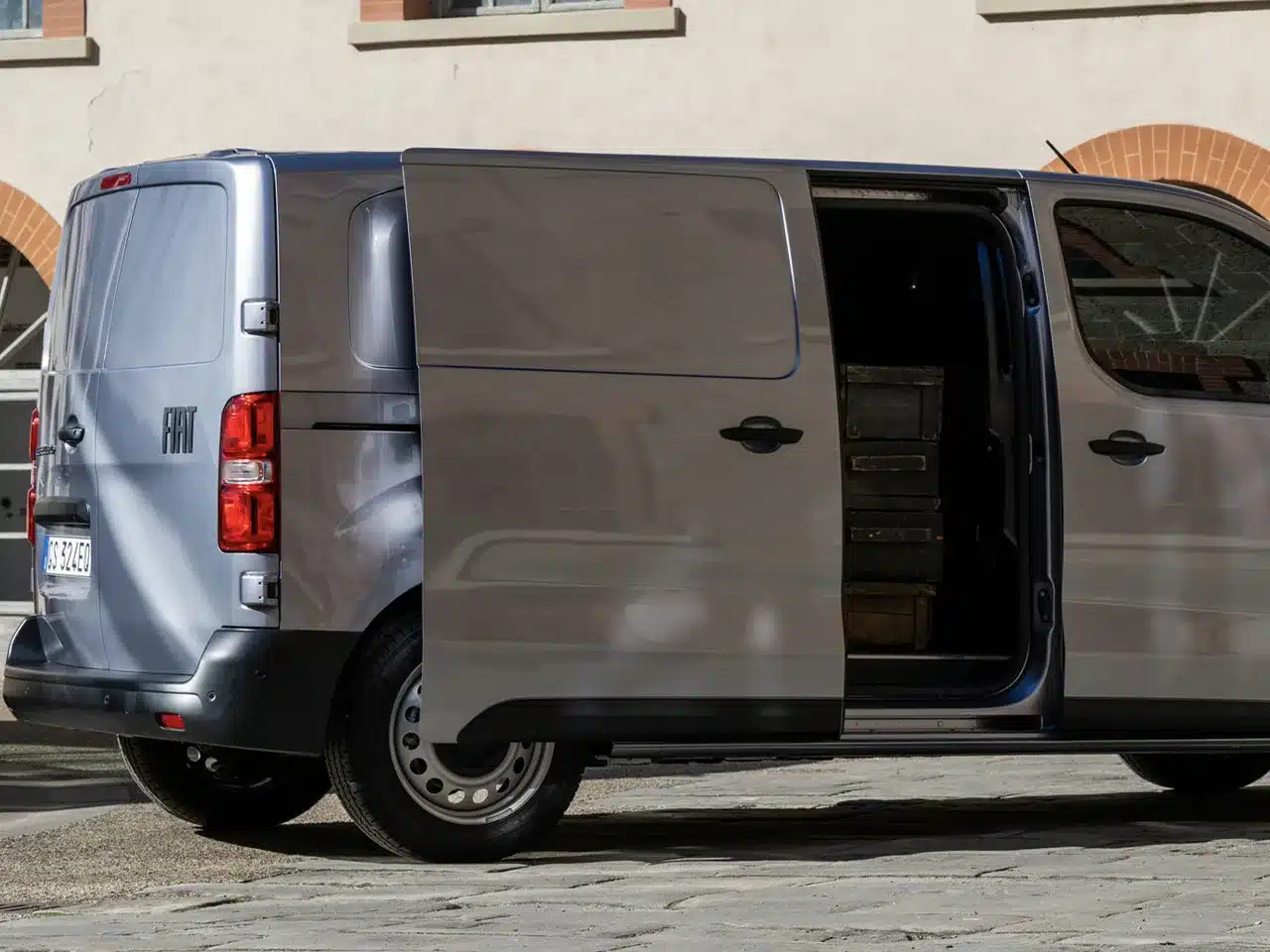 Fiat Scudo Transporter mit offener Schiebetür parkend, gefüllt mit Transportkisten