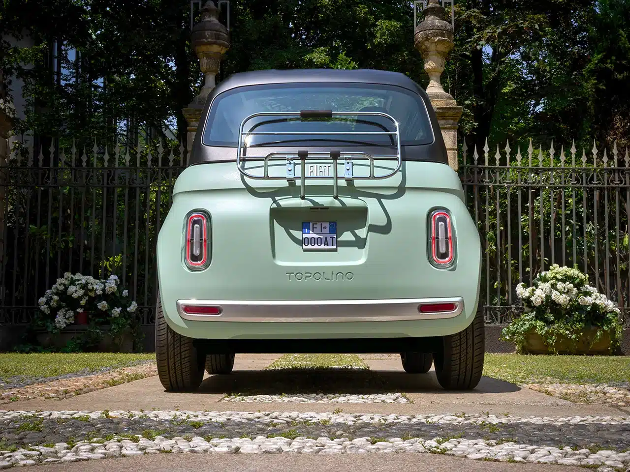 Fiat Topolino Verde Vita, Rückansicht mit Gepäckträger, im Garten vor schmiedeeisernem Zaun