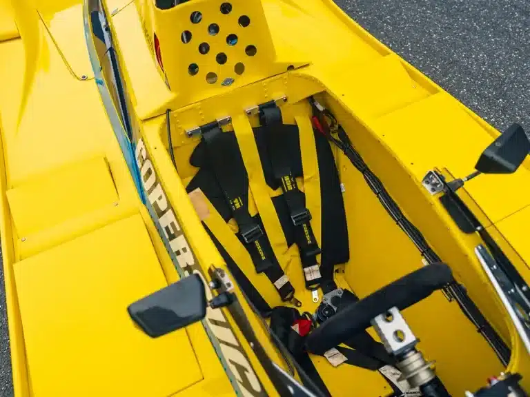 Detailaufnahme vom Cockpit des Fittipaldi F6A mit angeschnalltem Renngurt, Lenkrad und gelbem Monocoque.