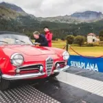 Roter Alfa Romeo Spider als Oldtimer bei einer Rallye auf einer Rampe in den Alpen.