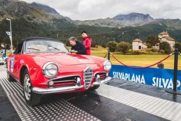 Roter Alfa Romeo Spider als Oldtimer bei einer Rallye auf einer Rampe in den Alpen.