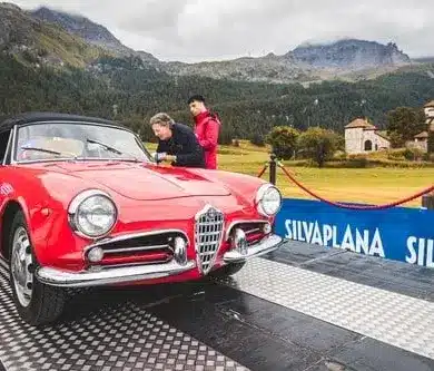 Roter Alfa Romeo Spider als Oldtimer bei einer Rallye auf einer Rampe in den Alpen.
