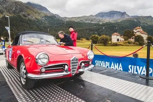 Roter Alfa Romeo Spider als Oldtimer bei einer Rallye auf einer Rampe in den Alpen.